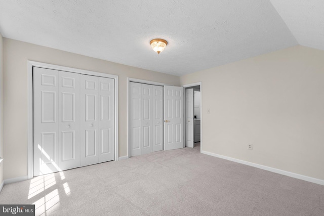 unfurnished bedroom with baseboards, two closets, and carpet flooring