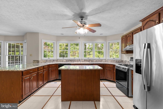 kitchen with stainless steel fridge with ice dispenser, a peninsula, gas range, under cabinet range hood, and a kitchen island