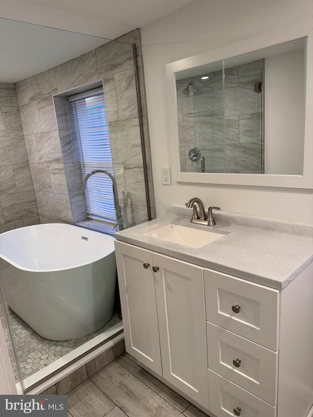 full bath with a stall shower, wood finished floors, a soaking tub, and vanity