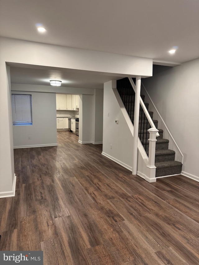 unfurnished living room featuring dark wood-type flooring, recessed lighting, stairway, and baseboards