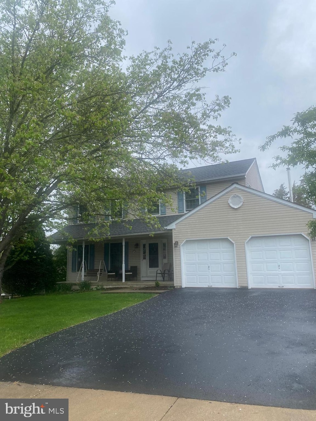 view of front of home with a porch, aphalt driveway, a front yard, and an attached garage