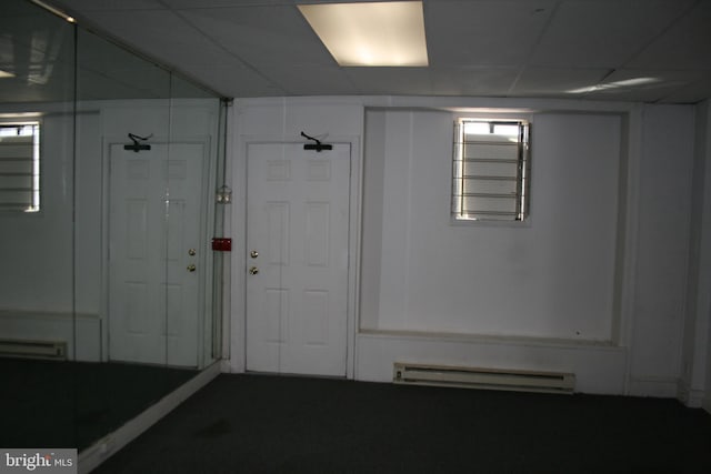 below grade area featuring a baseboard heating unit, a drop ceiling, and a baseboard radiator