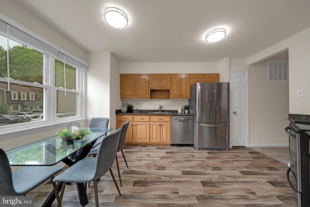 9120 Galbreth Ct, Springfield, VA 22153 - kitchen featuring stainless steel appliances, dark countertops, light wood finished floors, a sink, and baseboards