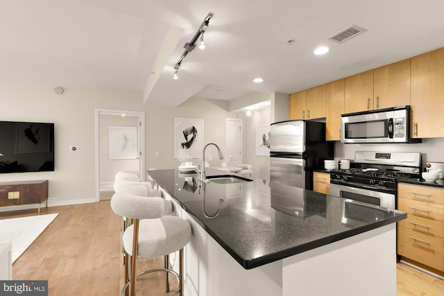 kitchen with light wood finished floors, a sink, rail lighting, visible vents, and appliances with stainless steel finishes