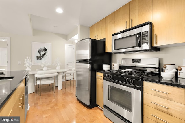 kitchen with dark stone countertops, recessed lighting, light brown cabinets, light wood-style flooring, and stainless steel appliances