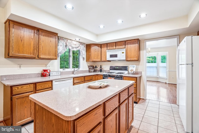 kitchen featuring white appliances, light tile patterned flooring, recessed lighting, a sink, and brown cabinets