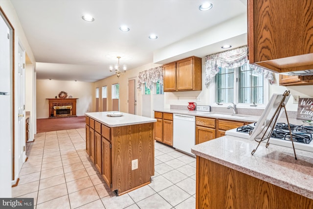 kitchen with dishwasher, a center island, a brick fireplace, a chandelier, and light tile patterned flooring