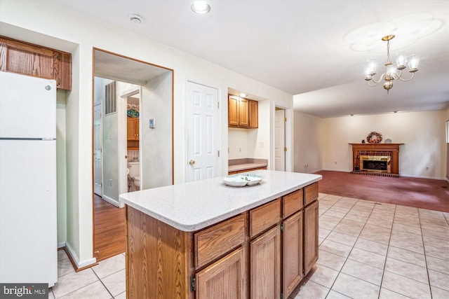 kitchen featuring freestanding refrigerator, light tile patterned floors, a center island, a chandelier, and open floor plan