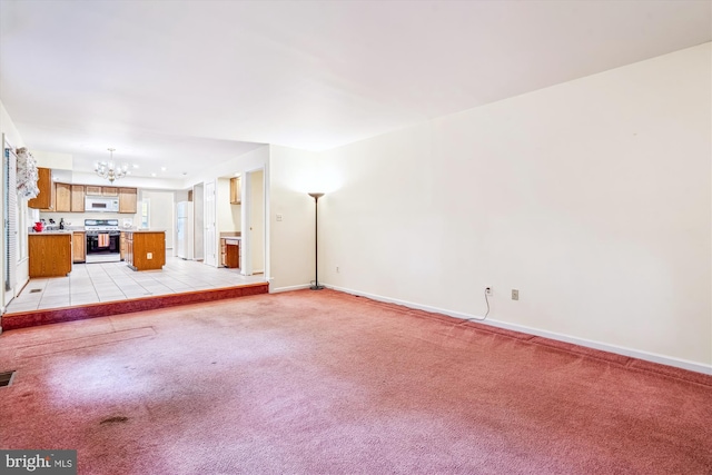 unfurnished living room featuring a chandelier, light colored carpet, and baseboards