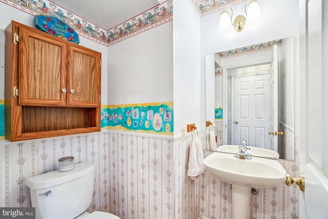 half bath with toilet and wallpapered walls