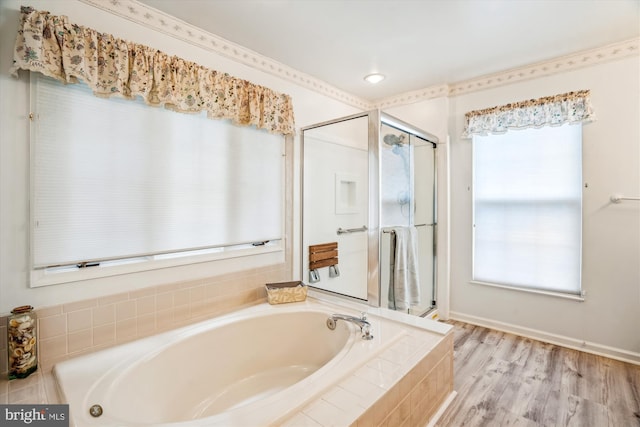 bathroom with a shower stall, a bath, and wood finished floors