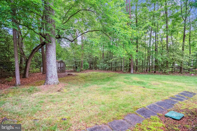 view of green lawn with a shed, an outdoor structure, and a view of trees