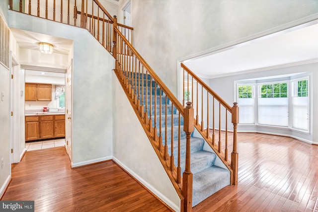 stairway with wood-type flooring, baseboards, and crown molding