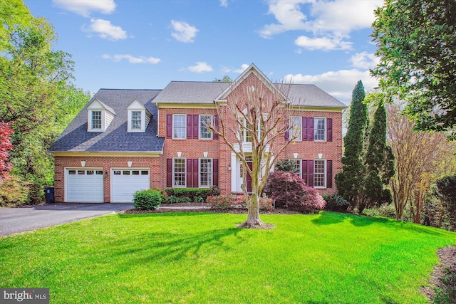 view of front of home featuring brick siding, a garage, a front yard, and aphalt driveway