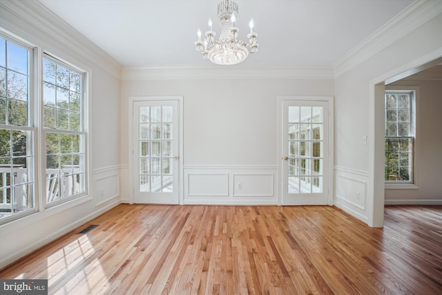 unfurnished dining area with crown molding, a notable chandelier, visible vents, and wood finished floors