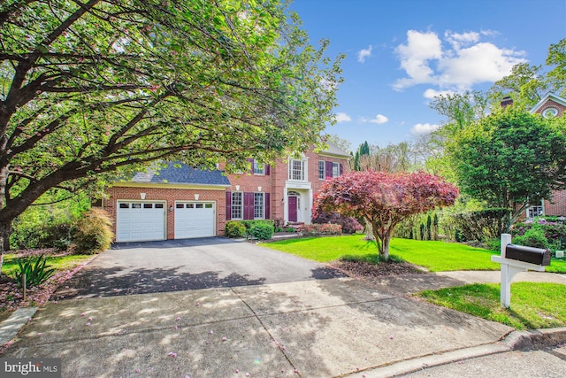 view of front of property featuring brick siding, an attached garage, aphalt driveway, and a front yard