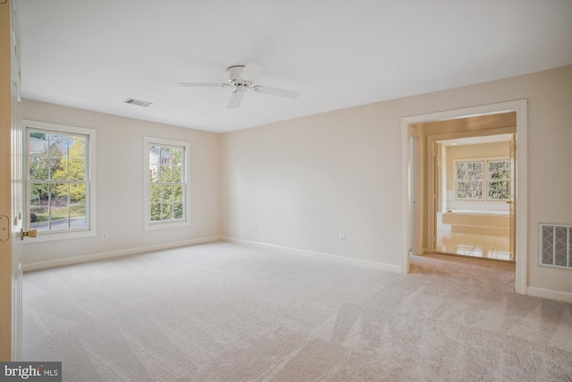 carpeted empty room with baseboards, ceiling fan, and visible vents