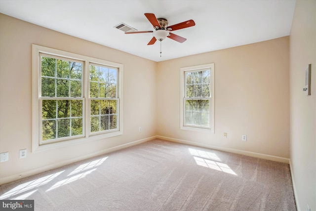 carpeted spare room featuring a healthy amount of sunlight, baseboards, and ceiling fan