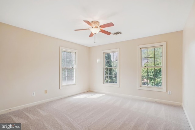 carpeted spare room with visible vents, baseboards, and ceiling fan