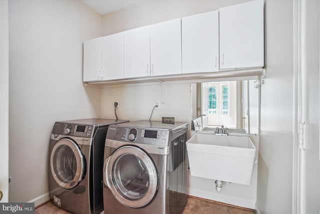 washroom with a sink, baseboards, cabinet space, and washer and clothes dryer