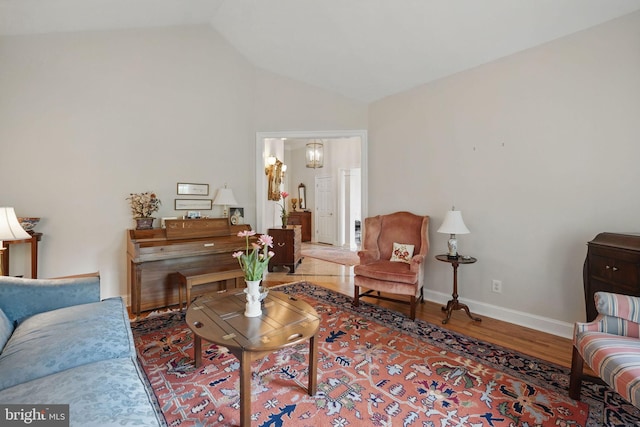 living area with baseboards, vaulted ceiling, and wood finished floors