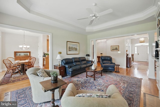 living room featuring crown molding, baseboards, light wood finished floors, and ceiling fan with notable chandelier