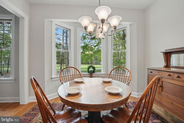 dining room featuring an inviting chandelier, baseboards, and light wood-type flooring