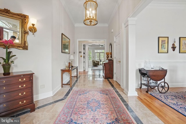 entryway featuring an inviting chandelier, baseboards, ornamental molding, and ornate columns