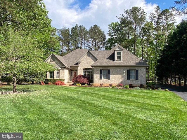 view of front of property with brick siding, a front lawn, and roof with shingles