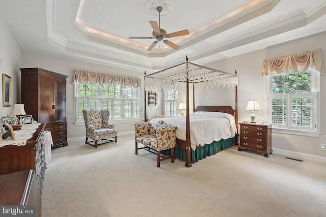 bedroom with visible vents, crown molding, light colored carpet, a raised ceiling, and baseboards