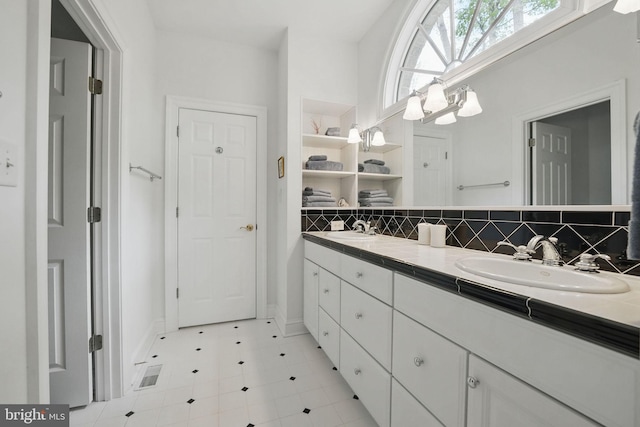 bathroom with a sink, baseboards, tasteful backsplash, and double vanity