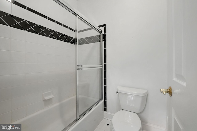 bathroom featuring baseboards, tile patterned floors, combined bath / shower with glass door, and toilet