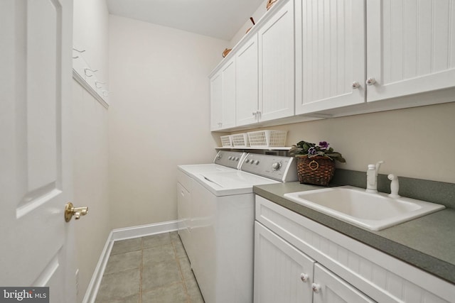 clothes washing area featuring cabinet space, light tile patterned flooring, washing machine and clothes dryer, a sink, and baseboards