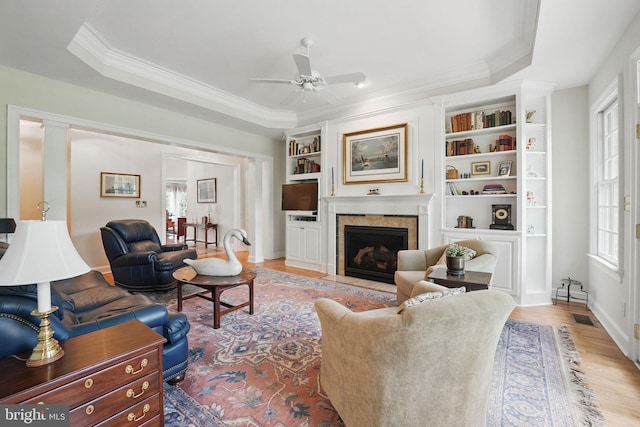 living room with visible vents, light wood-type flooring, crown molding, and ceiling fan