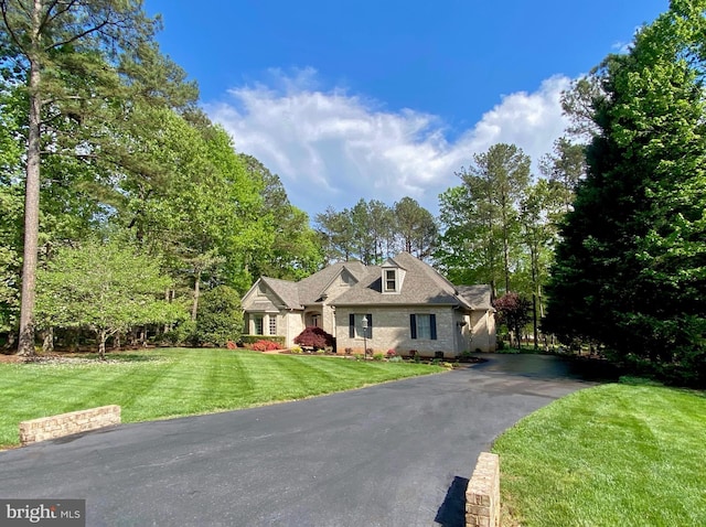 cape cod house with brick siding, driveway, and a front yard