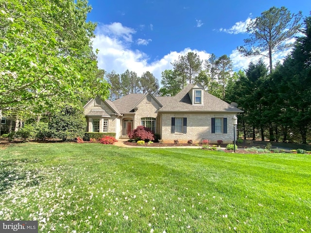 new england style home with brick siding, roof with shingles, and a front lawn