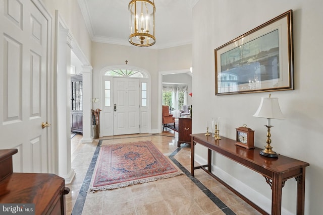 entrance foyer featuring a chandelier, baseboards, decorative columns, and ornamental molding