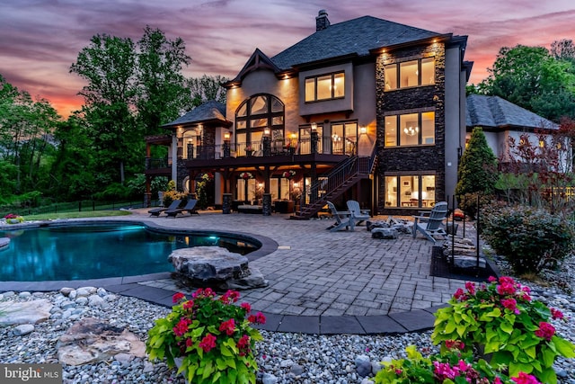 360 Fishing Creek Valley Rd, Harrisburg, PA 17112 - back of property at dusk featuring stairway, an outdoor fire pit, a patio, an outdoor pool, and a balcony