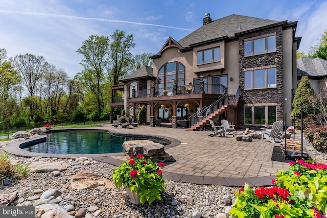 rear view of house with a patio, a fire pit, stairway, and an outdoor pool