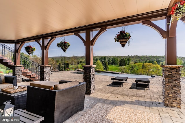 view of patio featuring stairway, an outdoor living space, and a wooded view