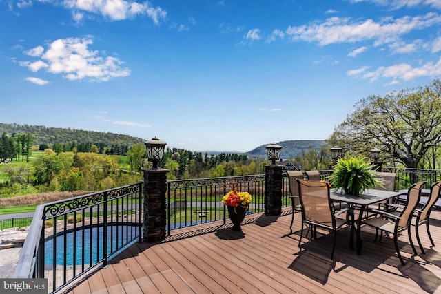 wooden deck with a fenced in pool and outdoor dining space