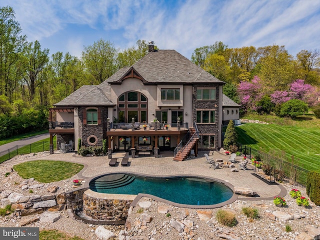 back of house with a fenced backyard, stucco siding, a balcony, and stairway