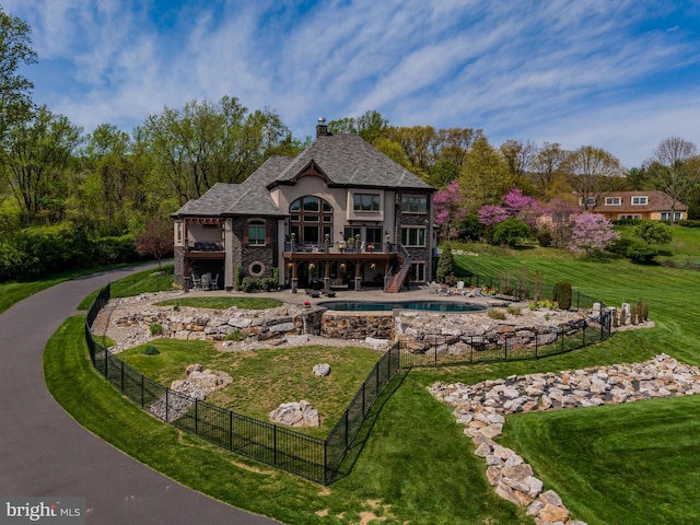 back of house with a chimney, a lawn, a wooden deck, a fenced backyard, and stairs
