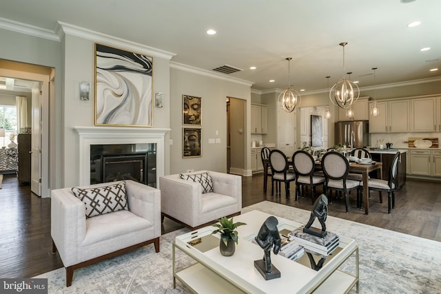 living area with dark wood-style floors, visible vents, a chandelier, and a glass covered fireplace