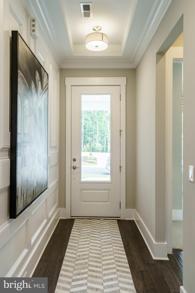 doorway to outside featuring ornamental molding, visible vents, dark wood-style flooring, and a raised ceiling