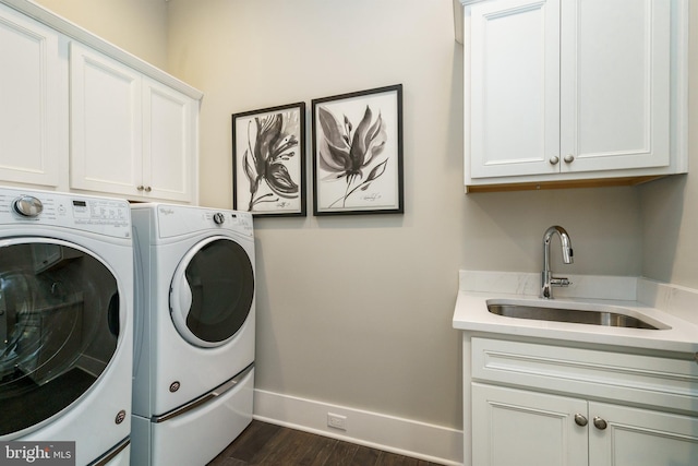 laundry area featuring a sink, baseboards, dark wood-style flooring, washer and dryer, and cabinet space