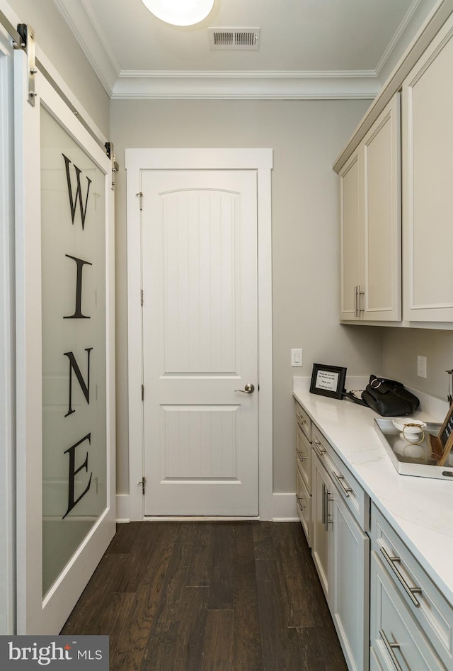 doorway featuring crown molding, visible vents, a barn door, baseboards, and dark wood finished floors
