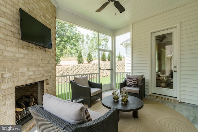 sunroom featuring ceiling fan, an outdoor living space with a fireplace, and a healthy amount of sunlight