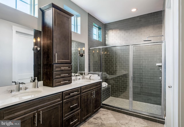 full bathroom with a wealth of natural light, a stall shower, and a sink