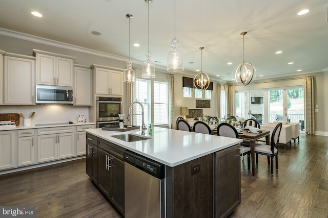 kitchen with crown molding, a sink, appliances with stainless steel finishes, a chandelier, and light countertops